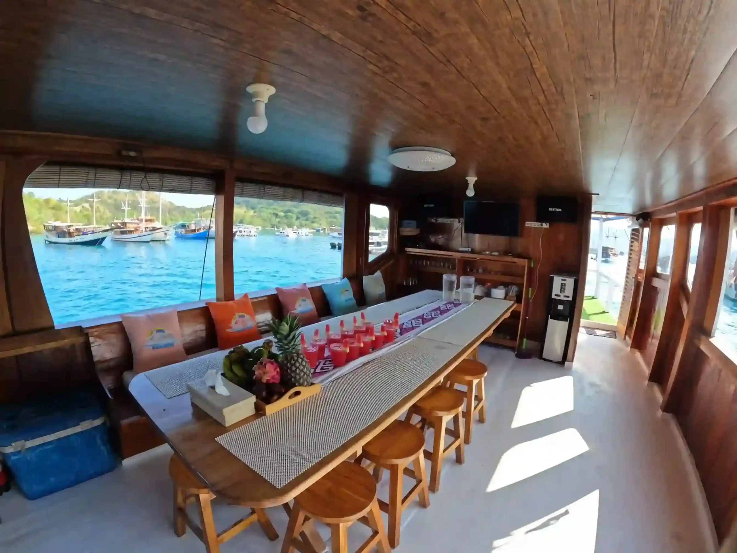 The long timber dining table in the saloon of a phinisi, open to the sea