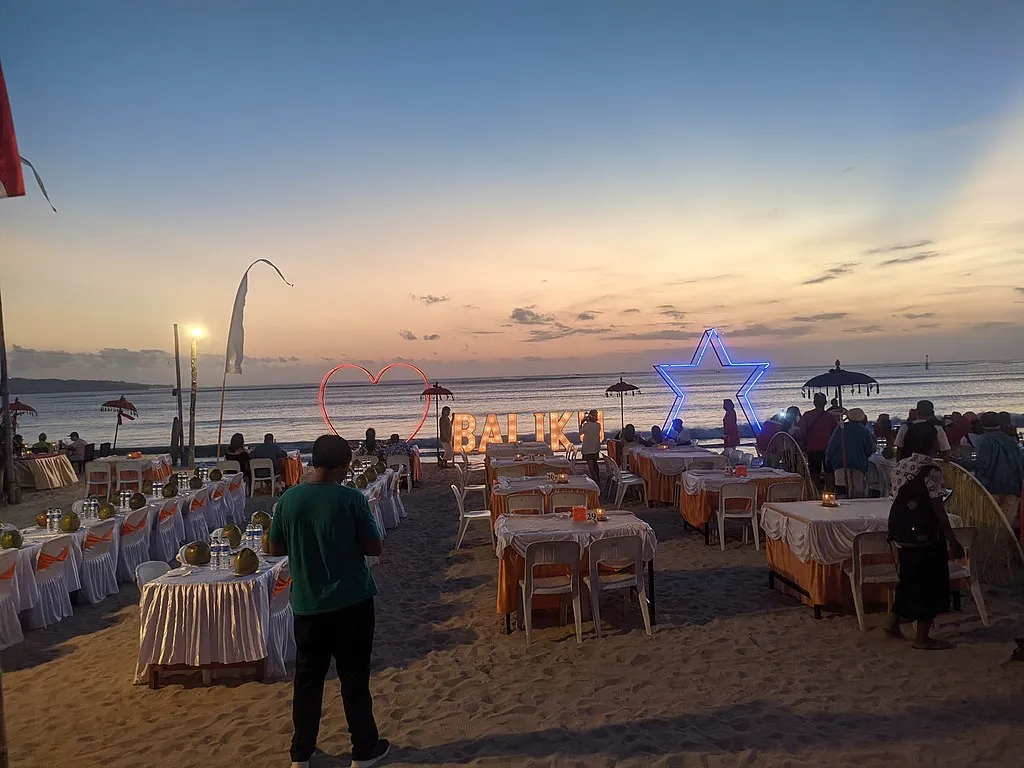Tables set on the sand at Jimbaran beach as the sun goes down