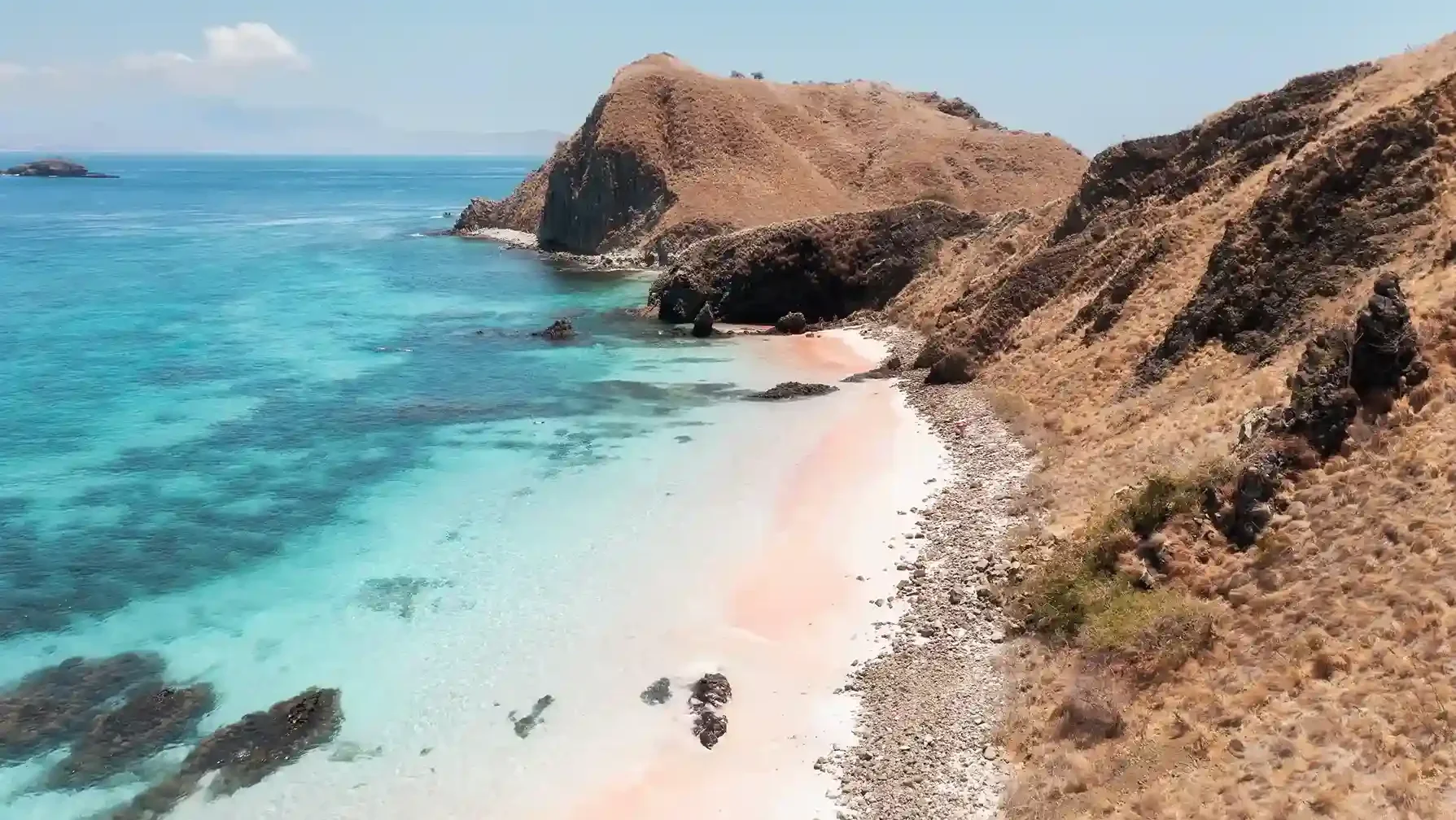 The coral-pink sand and clear shallows of Pink Beach in Komodo