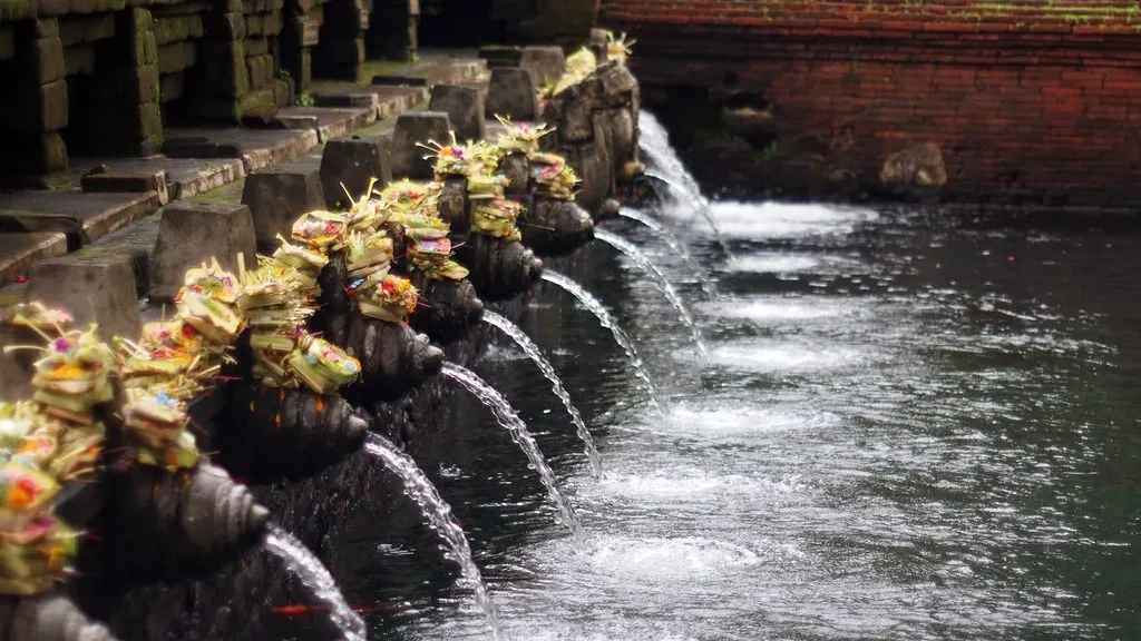 The row of stone purification spouts feeding the bathing pool at Pura Tirta Empul