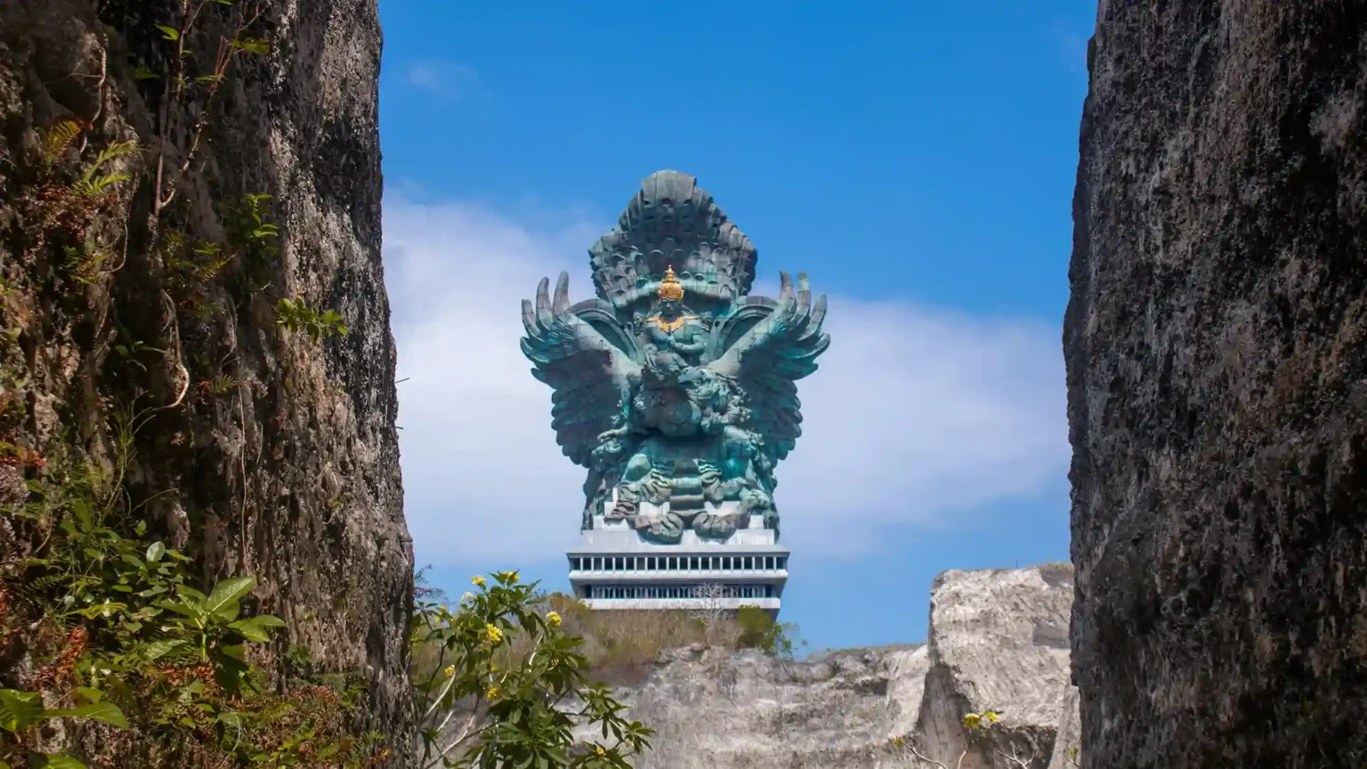 The Garuda Wisnu Kencana monument seen between the quarried limestone walls
